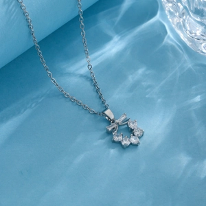 Silver bow flower wreath necklace with clear zircons on a blue water ripple background