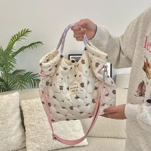 Detailed shot of a quilted cartoon bag featuring embroidered labels and woven handles