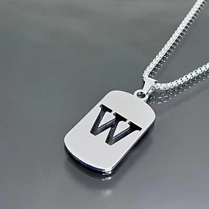 Macro detail of silver titanium steel pendant featuring hollowed-out letter W design