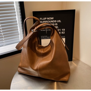 Detailed texture of brown soft leather tote bag on a metal table with soft lighting