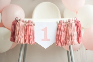 Detailed view of pink tassel high chair banner with number 1 for first birthday party