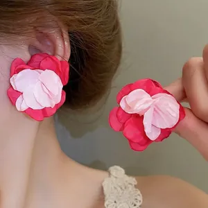 Macro detail of red and pink fabric flower earrings with layered petal texture