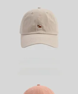 Detail of cute Corgi embroidery on cotton twill baseball caps in beige and pink colors