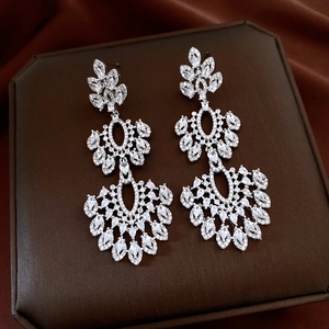 Close-up of cascading silver flower pendant earrings with zircon on brown display box