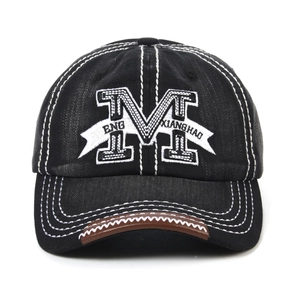 Detail of embroidered M letter on black denim baseball cap with white contrast stitching