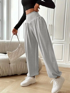 Women's high waist grey wide leg trousers paired with a black crop top in a minimalist room