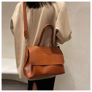 Detailed view of the brown crocodile-patterned PU leather handbag with wide strap