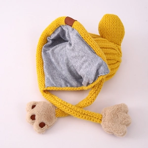 Detail der gelben Strickmütze mit grauem Baumwollfutter und warmen Plüsch-Bärentatzen