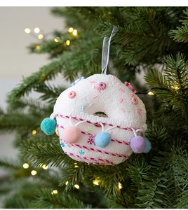 Detail of colorful plush candy ornament with soft pom-poms on a green Christmas tree
