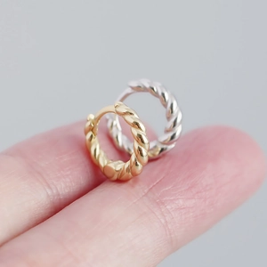 Macro shot of gold and silver twisted hoop earrings showing refined metal textures