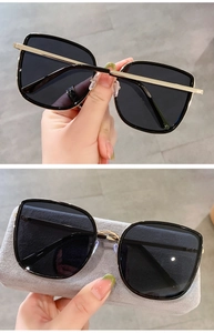 Detail of oversized square sunglasses with black lenses and slim gold metal frame