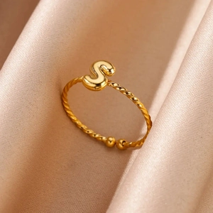 Detailed macro shot of 18k gold plated stainless steel twisted letter S ring on satin fabric