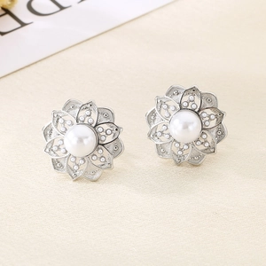 Close-up of silver flower earrings with white pearls and delicate filigree metal petals