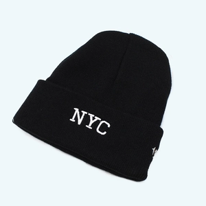 Detailed view of white NYC embroidery on a black ribbed knit beanie for winter
