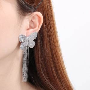 Detail of silver butterfly stud earring with long metal tassels shown on a model