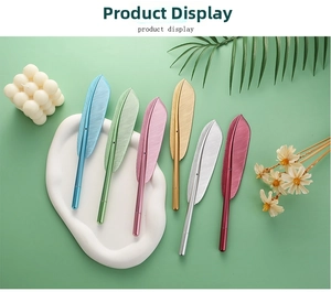Macro view of six metallic feather-shaped pens in assorted colors on a white tray