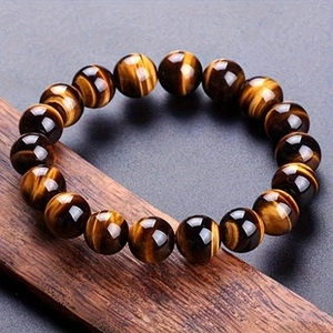 Macro shot of natural yellow wood grain tiger eye stone beads on a textured wooden base