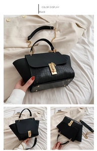 Detail of black crocodile texture wing bag with golden clasp and chain strap