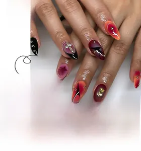 Detail of almond-shaped nails with red gradient effect and gold metal cross ornaments