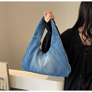 Vue détaillée montrant la texture en denim bleu délavé et les coutures de ce sac à main