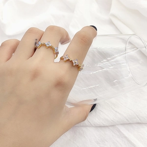 Elegant gold flower rings with light purple stones on hand holding a glass cup