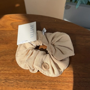 Detail of cream puff scrunchie with button accent on a wooden surface in close-up shot