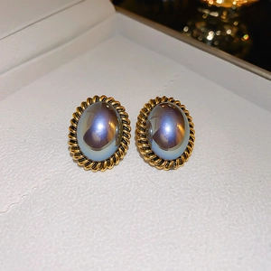 Macro d'oreilles ovales vintage à bordure dorée avec perles bleu-gris dans leur boîte