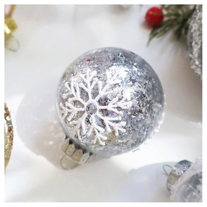 Macro view of a clear Christmas ball filled with silver sequins and white snowflake patterns