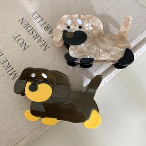 Süße Dackel-Haarklammern aus Acetat in Marmorbeige und Braun auf einem kunstvollen Buch