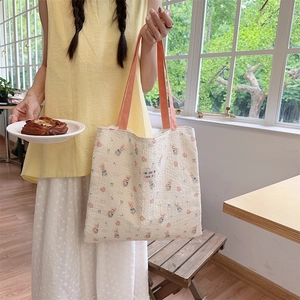 Detail of canvas tote bag with rabbit patterns and contrasting orange handles