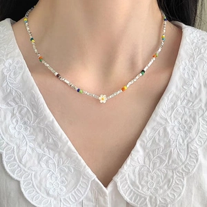 Macro detail of colorful beaded necklace featuring a white flower pendant and silver beads