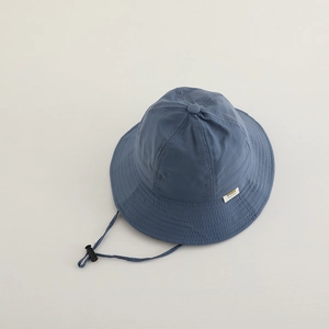 Détail du chapeau bleu avec cordon réglable et étiquette tissée minimaliste