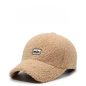 Detailed close-up of khaki teddy fleece baseball cap featuring a 'min' embroidered patch