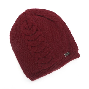 Detail of burgundy knit beanie with thick cable patterns and silver metal logo tag