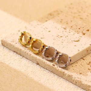 Detail of s925 silver heart hoop earrings with colorful zircon stones on stone surface