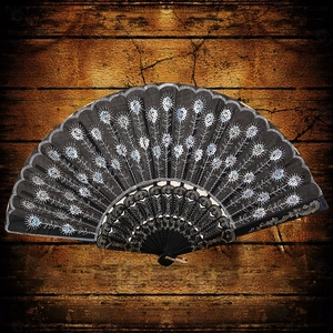Elegant black hand fan with white embroidery and silver sequins on dark wood background