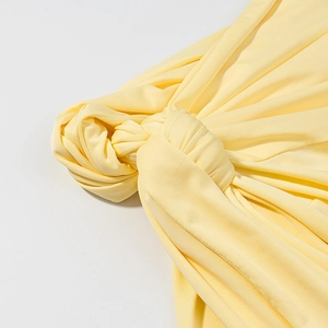 Détail de la robe tricotée jaune montrant le nœud élégant et la texture plissée du tissu