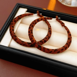 Détail macro de grandes créoles avec imprimé léopard floqué dans un écrin à bijoux noir