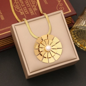 Elegant gold sunburst pendant necklace with central pearl on flat snake chain in a gift box