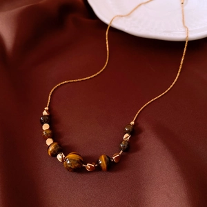 Detailed shot of tiger eye beads necklace on elegant red silk fabric background