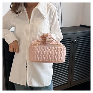 Dettaglio della borsa cosmetica in pelle rosa trapuntata con manico e motivo a rombi
