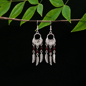 Detailed shot of ethnic tribal earrings with silver leaf tassels and dark red beads