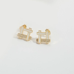 Close-up of lightning bolt earrings with gold frames, white enamel, and zircon accents