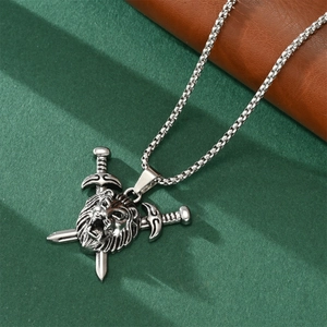 Close-up of silver lion head and cross swords pendant on a box chain for men