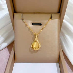 Détail d'un collier en or avec pendentif ovale jaune dans son écrin de bijoux marron
