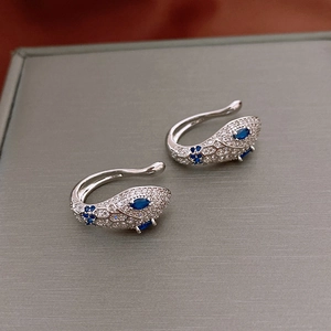 Close-up of silver snake ear clips with blue marquise zircon eyes and white diamonds