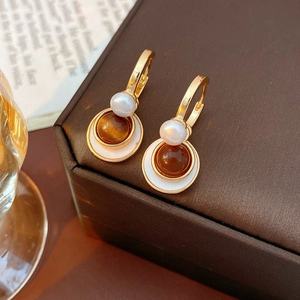 Close-up of vintage gold earrings with white pearl and brown round tiger eye stone