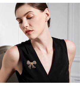 Detailed view of luxury rhinestone bow brooch with yellow gemstone on black sleeveless top