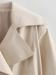 Gros plan détaillé des revers de trench-coat beige en tissu sergé avec coutures soignées