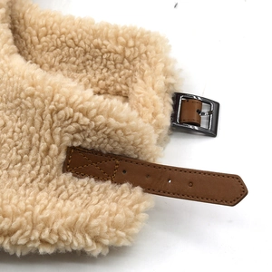Detailed close-up of sherpa fleece lining with brown leather strap and metal buckle